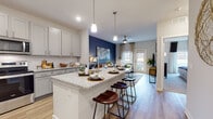 Located at 142 Patrick Murphy Dr in Morganton, NC, this thoughtfully designed single-floor residence offers a seamless blend of modern finishes and functional living spaces. The open-concept kitchen is a standout feature, boasting gray shaker-style cabinetry, granite countertops, a classic white subway tile backsplash, and a full suite of stainless steel appliances including a refrigerator, range, microwave, and dishwasher. A generously sized kitchen island with bar seating bridges the kitchen and living areas, making it ideal for entertaining. The living room is bathed in natural light from a sliding glass door that opens to a private balcony, and is complemented by light wood-style flooring and a ceiling fan. A bold navy accent wall adds a striking design element to the open living space. The bedroom is a serene retreat featuring plush carpeting, a dramatic dark accent wall, a ceiling fan, and ample natural light from large windows with blinds and curtains. The full bathroom is finished with granite countertops, wood-style flooring, and a soaking tub with a tile surround. A dedicated in-unit laundry room with side-by-side washer and dryer and overhead shelving completes this well-equipped residence.