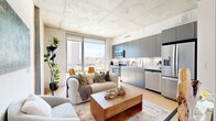 Located in the heart of downtown Phoenix at 440 E Van Buren St, this efficiently designed one-bedroom, one-bathroom residence offers a compelling blend of industrial and modern aesthetics. The open-plan living and kitchen area is anchored by striking exposed concrete ceilings and light wood flooring, creating an urban loft-inspired atmosphere. Floor-to-ceiling windows flood the space with natural light while framing views of the surrounding Phoenix skyline, enhancing the sense of openness throughout.

The kitchen is outfitted with sleek slate-gray cabinetry, stainless steel appliances, a white subway tile backsplash, and ample counter space — thoughtfully integrated into the living area for a seamless flow. The living space comfortably accommodates a full seating arrangement, making it both functional and inviting.

The spacious bedroom continues the concrete ceiling aesthetic, paired with large windows that invite natural light and city views. A short hallway connects the bedroom to the full bathroom, which features large-format tile flooring, a full soaking tub with white vertical tile surround, a warm wood-toned vanity with stone countertop, and clean white walls that contribute to a bright, spa-like feel. This residence delivers a polished, contemporary urban living experience in one of Phoenix's most vibrant neighborhoods.