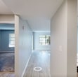 Located at 6701 Mallard Cove Rd in Jupiter, Florida, this 1-bedroom, 1-bathroom apartment offers 650 square feet of thoughtfully designed single-floor living space. The open-concept kitchen and living area is anchored by light wood-look vinyl flooring that runs throughout the main living space, complemented by neutral gray walls and a textured ceiling. The kitchen is well-appointed with gray shaker-style cabinetry, striking white quartz countertops with subtle veining, stainless steel appliances including a refrigerator, range, and microwave, and a deep single-basin sink. A sliding glass door in the living room opens to a private balcony, inviting natural light and views of the surrounding Florida greenery. The bedroom, measuring 150 square feet, features plush wall-to-wall carpeting, a window with blinds, and direct access to a hallway with a closet for additional storage. The bathroom is finished with wood-look tile flooring, a gray vanity with a white quartz top, and a full tub-shower combination with large-format white tile surround and chrome fixtures. A hallway connects the main living areas, completing this clean and functional floor plan.