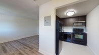 Located at 1210 NW 13th St in Boca Raton, Florida, this single-floor residence offers a clean, updated interior with a cohesive modern aesthetic throughout. Light-toned wood-style flooring runs through the main living areas and bedrooms, creating a warm and consistent look that ties the space together.

The kitchen is a standout feature, finished with rich dark espresso cabinetry that extends to the ceiling for ample storage. Light countertops provide contrast, while a subtle tile backsplash adds texture. Black appliances — including a full-size refrigerator, range, dishwasher, and over-the-range microwave — complete the functional setup. The kitchen transitions seamlessly into the main living area via an open passthrough layout.

The living area is generously proportioned, featuring a ceiling fan with light fixture and a textured ceiling. A dedicated hallway leads to the private quarters, with multiple well-sized bedrooms, each outfitted with the same wood-style flooring and crisp white walls. Several bedrooms benefit from windows that invite natural light and offer views of the surrounding greenery. One bedroom features access to a closet space, adding practical storage.

Throughout the home, white trim and neutral walls maintain a bright, airy atmosphere. The single-story layout offers straightforward, accessible flow between all areas of the residence.