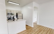 This 720-square-foot, one-bedroom, one-bathroom apartment at 2031–2055 Ovaltine Ct in Villa Park, IL is designed with clean, modern aesthetics throughout. The open living room features light wood-style flooring, large windows, a sliding glass door to a private balcony, and a ceiling fan, creating a bright and airy atmosphere with ample natural light and outdoor views. The galley-style kitchen is outfitted with stainless steel appliances including an electric range, built-in microwave, refrigerator, and dishwasher, complemented by white quartz countertops, a double stainless steel sink with a matte black faucet, white subway tile backsplash, and warm gray cabinetry with black hardware. The 180-square-foot bedroom offers plush carpeting, a ceiling fan, natural light from windows, and direct access to a dedicated closet. The bathroom features a full tub/shower combo adorned with large-format marble-style tile and matte black fixtures. A dedicated laundry room houses a full-size washer and dryer. A hallway connects all rooms efficiently, completing this well-appointed and functional floor plan.