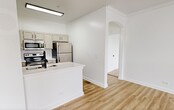 This 720-square-foot, one-bedroom, one-bathroom apartment at 2031–2055 Ovaltine Ct in Villa Park, IL is designed with clean, modern aesthetics throughout. The open living room features light wood-style flooring, large windows, a sliding glass door to a private balcony, and a ceiling fan, creating a bright and airy atmosphere with ample natural light and outdoor views. The galley-style kitchen is outfitted with stainless steel appliances including an electric range, built-in microwave, refrigerator, and dishwasher, complemented by white quartz countertops, a double stainless steel sink with a matte black faucet, white subway tile backsplash, and warm gray cabinetry with black hardware. The 180-square-foot bedroom offers plush carpeting, a ceiling fan, natural light from windows, and direct access to a dedicated closet. The bathroom features a full tub/shower combo adorned with large-format marble-style tile and matte black fixtures. A dedicated laundry room houses a full-size washer and dryer. A hallway connects all rooms efficiently, completing this well-appointed and functional floor plan.