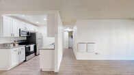 Located along Pacific Coast Highway in Torrance, California, this two-bedroom, one-bathroom residence offers a thoughtfully designed single-floor layout with clean, contemporary finishes throughout. Wood-look plank flooring flows seamlessly across the living room, hallway, and bedrooms, lending a cohesive and modern aesthetic to the entire space.

The open living room is bright and welcoming, featuring a ceiling fan and large sliding glass doors that open to a private patio, allowing natural light to fill the room and providing a pleasant outdoor connection. The kitchen is efficiently laid out and features white shaker-style cabinetry with matte black hardware, granite-look countertops, a mosaic tile backsplash, a stainless steel sink, and stainless steel appliances. A peninsula countertop opens the kitchen toward the main living area.

The primary bedroom is generously sized and includes a barn-style closet door, while the second bedroom offers a window with a view of surrounding trees, creating a serene atmosphere. Both rooms feature the same warm-toned wood-look flooring and a textured ceiling.

The bathroom is well-appointed with a granite-look vanity countertop, a vessel-style sink, matte black fixtures, a framed mirror, and a glass-door tub and shower combination. Clean white walls and wood-look flooring complete the cohesive design of this comfortable Torrance residence.
