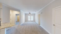This single-floor residence offers a thoughtfully designed layout that balances comfort and functionality. The spacious living area features plush wall-to-wall carpeting, crisp white walls adorned with crown molding, and a ceiling fan with a light fixture. French doors with slatted blinds invite natural light and provide access to an outdoor area, creating a bright and airy ambiance throughout.

The open-concept kitchen is outfitted with white shaker-style cabinetry, granite countertops, a tile backsplash, and a full suite of stainless steel appliances including a range, over-the-range microwave, and refrigerator. A kitchen island with a sink adds additional prep space and connects seamlessly to the adjoining living and dining areas, which feature warm hardwood-style flooring.

The bedrooms are generously sized, each with plush carpeting and ceiling fans. One bedroom features French door access to an outdoor balcony, while another opens to a private hallway leading to the bathroom.

The bathroom is well-appointed with a dual-sink vanity topped with granite countertops, white cabinetry, brushed nickel hardware, and a Hollywood-style vanity light. A separate tub and shower combo with brushed nickel fixtures completes the space. Throughout, the residence maintains a clean, neutral palette that offers a welcoming and move-in-ready environment.