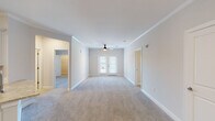 This single-floor residence offers a thoughtfully designed layout that balances comfort and functionality. The spacious living area features plush wall-to-wall carpeting, crisp white walls adorned with crown molding, and a ceiling fan with a light fixture. French doors with slatted blinds invite natural light and provide access to an outdoor area, creating a bright and airy ambiance throughout.

The open-concept kitchen is outfitted with white shaker-style cabinetry, granite countertops, a tile backsplash, and a full suite of stainless steel appliances including a range, over-the-range microwave, and refrigerator. A kitchen island with a sink adds additional prep space and connects seamlessly to the adjoining living and dining areas, which feature warm hardwood-style flooring.

The bedrooms are generously sized, each with plush carpeting and ceiling fans. One bedroom features French door access to an outdoor balcony, while another opens to a private hallway leading to the bathroom.

The bathroom is well-appointed with a dual-sink vanity topped with granite countertops, white cabinetry, brushed nickel hardware, and a Hollywood-style vanity light. A separate tub and shower combo with brushed nickel fixtures completes the space. Throughout, the residence maintains a clean, neutral palette that offers a welcoming and move-in-ready environment.
