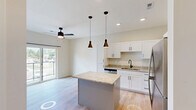 Located on Nicholasville Road in Lexington, Kentucky, this well-appointed 2-bedroom, 1-bathroom unit offers a thoughtfully designed single-floor layout. The open-concept kitchen and living area serves as the heart of the home, featuring crisp white shaker cabinetry, granite countertops, a central island with pendant lighting, and a full suite of stainless steel appliances including a range, built-in microwave, dishwasher, and refrigerator. Recessed lighting and a ceiling fan with a light kit illuminate the space, while light hardwood-style flooring extends throughout the main living areas, lending a clean and contemporary feel. A sliding glass door in the living area provides access to an outdoor balcony and brings in natural light. Both bedrooms are carpeted and offer ceiling fans, large windows with outdoor views of the surrounding neighborhood, and generous closet access — four closets total are distributed throughout the unit. The bathroom features a granite-topped vanity with white cabinetry, consistent with the home's cohesive modern aesthetic. A dedicated laundry area and a connecting hallway round out the floor plan. Neutral white walls and modern black hardware fixtures throughout create a bright, move-in-ready environment.