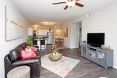 This single-floor residence offers a thoughtfully designed layout that balances comfort and functionality across its living spaces. The open living room serves as the heart of the home, featuring rich wood-style flooring, a ceiling fan with light fixture, and large windows that invite abundant natural light. The space is generously sized, providing ample room for both lounging and entertaining.

The kitchen is well-equipped with stainless steel appliances, including a refrigerator, range, microwave, and dishwasher. White shaker-style cabinetry pairs with dark countertops, and a pass-through window connects the kitchen to the living area, enhancing the open feel.

The residence includes multiple bedrooms, each finished with plush carpeting, ceiling fans, and windows providing natural light. The bedrooms offer comfortable proportions suitable for full or queen-sized beds along with additional furniture.

Two full bathrooms serve the home, each featuring wood-style flooring, a tub-shower combination with sliding glass doors, a white vanity with ample counter space, and overhead cabinetry for storage. The neutral, warm-toned color palette carried throughout the residence creates a cohesive and inviting atmosphere from room to room.