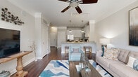 Located in the Collier Hills neighborhood of Atlanta, Georgia, this single-floor residence offers a thoughtfully designed open-concept layout that seamlessly connects the living, dining, and kitchen areas. Rich hardwood flooring flows throughout the main living spaces, complemented by crown molding and ceiling fans that add a refined touch to the interior.

The kitchen is a standout feature, outfitted with crisp white cabinetry, granite countertops, a classic subway tile backsplash, and a full suite of stainless steel appliances including a refrigerator, range, microwave, and dishwasher. Pendant lighting illuminates the kitchen island, which also serves as a convenient breakfast bar with seating.

The living room is bright and welcoming, with a bank of large windows that invite an abundance of natural light and offer views of the surrounding greenery. A ceiling fan anchors the space, which is further defined by elegant crown molding.

The bedrooms are carpeted for comfort and feature ceiling fans, ample natural light from well-sized windows, and generous closet space. The bathroom is finished with clean white tile, a soaking tub, and a shower combination, set on light-toned tile flooring. The overall palette throughout the residence is neutral and warm, creating a cohesive and inviting atmosphere.