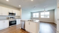 This thoughtfully designed single-floor residence offers a seamless open-concept layout encompassing a kitchen, living room, bedroom, and bathroom. Warm wood-look flooring flows consistently throughout the entire space, creating visual continuity and a welcoming ambiance.

The kitchen serves as a functional centerpiece, anchored by a large island with granite countertops and a double-basin sink. White shaker-style cabinetry lines the walls and extends to the ceiling for generous storage, complemented by granite countertops and a full suite of stainless steel appliances including a refrigerator, electric range, built-in microwave, and dishwasher.

The open living area is bathed in natural light from dual windows and features a ceiling fan overhead, with views of the surrounding neighborhood. The bedroom offers a comfortable footprint, its own ceiling fan, and a window providing additional natural light and outdoor views.

The bathroom is finished with the same attention to detail, featuring white shaker vanity cabinetry with granite countertops, a large mirror, and a tiled tub-shower combination. Clean neutral wall tones and recessed lighting round out the polished, modern aesthetic of this well-appointed residence.