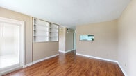 Located at 2801 Walnut Bend Lane in Houston, TX, this 1-bedroom, 1-bathroom unit offers a well-utilized single-floor layout designed for comfortable everyday living. The living area features warm hardwood-style flooring that runs throughout the space, complemented by neutral beige walls and a textured ceiling. A standout feature of the living room is the built-in shelving unit, providing ample storage and display space, while a pass-through window connects the living area to the kitchen, enhancing the open feel. The kitchen showcases light cabinetry with a subtle tile backsplash, keeping the space clean and functional. The spacious bedroom benefits from a large window dressed with horizontal blinds, allowing for generous natural light and outdoor views. The room's generous footprint offers flexibility for a variety of furniture arrangements. The bathroom is equipped with a wide vanity featuring a speckled countertop, white cabinetry below, and a mirrored medicine cabinet above, providing practical storage. A dedicated closet adds to the unit's organizational capacity. Consistent hardwood-style flooring ties the entire space together, creating a cohesive and inviting atmosphere throughout.