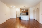 This single-story unit in Pooler, Georgia presents a well-organized floor plan with consistent finishes throughout. Rich hardwood flooring extends across the main living areas, complementing the neutral-toned walls and creating a warm, cohesive aesthetic. The spacious living room receives generous natural light through a sliding glass door fitted with vertical blinds, opening to an outdoor balcony area with views of surrounding greenery.

The kitchen is positioned at the heart of the unit, featuring an open layout with a peninsula breakfast bar illuminated by pendant lighting. Rich wood cabinetry extends to the ceiling, providing ample storage, while granite-style countertops and a full suite of black Whirlpool appliances — including a range, over-the-range microwave, and refrigerator — complete the functional workspace.

The bedrooms offer a quieter retreat, finished with plush carpeting and windows fitted with horizontal blinds that frame outdoor views. One bedroom connects directly to a private bathroom, which features a wood vanity with granite countertops, an undermount sink, and hardwood flooring that mirrors the main living areas. Additional rooms provide flexible spaces well-suited for various uses.