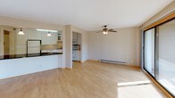 Located at 3185 Karth Rd in White Bear Lake, Minnesota, this single-floor residence offers a practical and comfortable layout with a clean, neutral aesthetic throughout. The open-concept living area is finished with light hardwood-style flooring, a ceiling fan with light fixture, and baseboard heating. Large windows flood the space with natural light and offer views of surrounding greenery, while a sliding glass door provides direct access to an outdoor area. The kitchen is thoughtfully designed with white raised-panel cabinetry, some featuring frosted glass inserts, and light-toned countertops. It is equipped with a full suite of white appliances including an electric range with microwave above, dishwasher, and refrigerator, along with a double stainless steel sink. A pass-through or peninsula connects the kitchen to the main living space, enhancing the open flow. The bedroom features wall-to-wall carpet, a ceiling fan, a wall-mounted AC unit, a baseboard heater, and a window with natural light. The full bathroom includes a vanity with a speckled countertop, a large mirror, towel bars, and a tub and shower combination with white tile surround. Overall, the space presents a functional and well-maintained interior suited for comfortable everyday living.