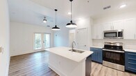 Located at 3530 Harbor Pointe Cir in Fruitland Park, FL, this well-appointed 3-bedroom, 2-bathroom single-floor home offers a thoughtfully designed layout with modern finishes throughout. The open-concept living area seamlessly connects the kitchen, dining, and living spaces, all finished with warm wood-look luxury vinyl plank flooring. The kitchen is a standout feature, showcasing a large center island with an undermount sink and white quartz countertop, striking two-tone cabinetry — white uppers paired with bold navy-blue lowers — a classic subway tile backsplash, stainless steel appliances, and industrial-style pendant lighting. Ceiling fans throughout enhance comfort and airflow. A sliding glass door opens to a private balcony, allowing natural light to pour in. The three bedrooms are carpeted and bright, each with windows framing outdoor greenery and ceiling fans. The spacious primary bedroom offers a generous footprint with ample closet space. Both bathrooms feature wood-look flooring and stylish navy vanities. A dedicated laundry room with a full-size washer and dryer, a pantry, and a utility room add practical convenience to this clean, contemporary home.