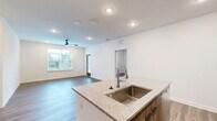 Located in Saint Augustine, FL, this thoughtfully designed 2-bedroom, 1-bathroom residence offers a clean, contemporary aesthetic across a single floor. Wood-look plank flooring runs throughout the home, creating a warm and cohesive feel in every room. The open-concept kitchen and living area serves as the heart of the home, featuring a central island with granite countertops, modern flat-front cabinetry in a warm wood tone, a full suite of stainless steel appliances, and recessed lighting. The kitchen flows seamlessly into the living room, which benefits from multiple windows fitted with blinds that allow for controlled natural light. Ceiling fans are present in the main living areas and bedrooms, enhancing comfort year-round. The spacious primary bedroom offers generous proportions and views of the surrounding greenery. The second bedroom is well-sized and equally bright. A dedicated walk-in closet with built-in wire shelving provides ample storage. The bathroom is finished with clean white walls, a glass-enclosed walk-in shower, a granite-topped vanity, and tall wood-toned cabinetry. The overall design is bright, neutral, and move-in ready, reflecting a modern and functional living environment.