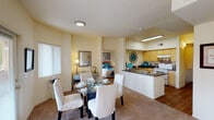 This single-floor residence offers a thoughtfully designed layout that seamlessly connects its key living spaces. The open-concept dining and living area is bright and welcoming, featuring soft carpet flooring, large windows that invite natural light, and a comfortable flow between spaces. The dining area accommodates a full-sized table, while the adjacent living room provides a relaxed retreat with ample room for seating.

The kitchen is well-equipped and functional, featuring a U-shaped layout with light wood cabinetry, dark laminate countertops, a white appliance suite including a range and dishwasher, and warm wood-tone flooring. Generous counter space makes it ideal for everyday cooking and entertaining.

The primary bedroom is a calm, carpeted space with a large window and room for a full furniture arrangement. The second bedroom offers equal versatility, complete with a walk-in closet and space for a desk, making it suitable as a guest room or home office. Both bathrooms are finished with dark countertops, white fixtures, a tub-shower combination, and rich wood-tone flooring.

Completing the layout is a dedicated in-unit laundry room housing a full-sized washer and dryer beneath overhead cabinetry, adding everyday convenience to this well-rounded residence.