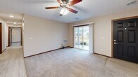 This single-floor residence in Hutchinson, Minnesota offers a practical and comfortable layout with two bedrooms, two bathrooms, and an attached garage. The open-concept kitchen and living area serves as the heart of the home, featuring rich dark wood cabinetry, granite-style countertops, stainless steel appliances including a refrigerator and range, and a breakfast bar peninsula. Light wood-style flooring runs through the kitchen and transitions to plush carpeting in the living and bedroom areas. Ceiling fans with integrated lighting are found throughout, adding both comfort and style. The spacious living room is bright and welcoming, with a bold black front entry door and access to natural light through sliding and standard windows. The primary bedroom is generously sized, with a large window overlooking the outdoors. The second bedroom offers convenient access to in-unit washer and dryer connections. Both bathrooms are finished with warm wood vanities, white countertops, and light tile flooring; one includes a full tub-shower combination. Two closets provide ample storage. The attached garage features drywalled walls and a direct interior entry door, offering secure and convenient parking.