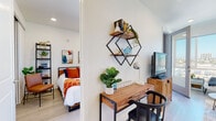 Located at 3918 Arizona St in San Diego's vibrant North Park neighborhood, this single-floor unit offers a thoughtfully designed layout with modern finishes throughout. The kitchen is outfitted with stainless steel appliances, including a full range, microwave, and dishwasher, complemented by two-tone cabinetry—crisp white upper cabinets paired with warm wood-toned lower cabinets—and a clean white quartz countertop with a subway tile backsplash. Light wood-style flooring flows throughout the space, lending warmth and cohesion. The living area is bright and inviting, featuring large windows and access to an outdoor balcony that captures sweeping city views of the San Diego skyline. The bedroom provides a comfortable retreat with a built-in closet with sliding doors and ample wall space for storage and décor. A dedicated workspace area with geometric wall shelving adds functional versatility to the unit. The bathroom features a wide vanity with a wood-tone cabinet base, white countertop, a full soaking tub with shower, and large-format tile flooring. Clean white walls and recessed lighting throughout the unit create a bright, airy ambiance, while the overall design reflects a contemporary aesthetic suited to modern urban living.