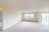 Located at 2445 Lyttonsville Rd in Silver Spring, Maryland, this one-bedroom, one-bathroom residence offers a thoughtfully arranged single-floor layout totaling nearly 900 square feet. The expansive living room is carpeted and bathed in natural light through large windows dressed with vertical blinds, complemented by a baseboard heating unit. An adjoining area opens to a sliding glass door that leads to a private balcony, and a ceiling fan adds comfort to the space. The dining room flows naturally from the living area, creating a cohesive and functional common space. The kitchen features warm wood cabinetry with ample upper and lower storage, granite-style countertops, a gas range, dishwasher, full-size refrigerator, and light tile flooring — providing a practical and well-appointed cooking environment. The generously sized primary bedroom is carpeted and bright, with access to a dedicated closet. Two additional closets throughout the unit offer exceptional storage capacity. The bathroom is finished with white tile surrounding the tub-shower combination, a vanity with under-sink cabinetry, and a mirrored medicine cabinet. The overall aesthetic is clean and neutral, with light-toned walls and carpet throughout the main living spaces.