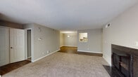 Located at 1403 Cobb Crossing SE in Smyrna, Georgia, this single-floor residence offers a thoughtfully arranged layout with a comfortable, neutral aesthetic throughout. The open living and dining area is generously proportioned, featuring plush carpeting in the living space and wood-look flooring in the dining area. A ceiling fan overhead and large windows, along with a sliding glass door leading to an outdoor deck, allow ample natural light and views of the surrounding greenery. A dark tile-surround fireplace serves as a focal point in the living room, adding warmth and character.

The galley-style kitchen is well-appointed with white cabinetry, granite-look countertops, a mosaic tile backsplash, and black appliances including a gas range, refrigerator, and microwave. A walk-in pantry or utility closet is accessible directly from the kitchen. Wood-look flooring runs throughout the kitchen, complementing the cabinetry.

The bedrooms are carpeted and include ceiling fans, with one bedroom featuring direct access to a closet. Both bathrooms are finished with granite-look vanity tops, wood-look flooring, and tub-shower combinations, maintaining a clean and cohesive style. Neutral taupe walls and white trim unify the overall design of the space.