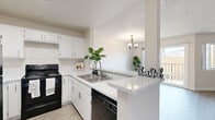 Located at 4335 Vineland Ave in the North Hollywood neighborhood of Los Angeles, this well-appointed two-bedroom, two-bathroom residence offers a thoughtfully designed single-level layout. Light wood-style flooring flows throughout the space, complemented by neutral-toned walls and textured ceilings that lend a clean, modern feel.

The open kitchen is a standout feature, showcasing crisp white cabinetry, granite-style countertops with a peninsula breakfast bar, a stainless steel sink, and black appliances including a refrigerator, electric range, and dishwasher. A chandelier elegantly marks the transition into the adjoining living room, which is bright and airy, enhanced by large sliding glass doors that open to a private balcony with outdoor views.

Both bedrooms are comfortably sized, with the primary bedroom offering generous proportions and access to a dedicated walk-in closet equipped with wire shelving. The two bathrooms are finished in a consistent white palette, each featuring a tub-shower combination, white vanity with storage, and large mirrors. Hallways connect the rooms efficiently, contributing to a functional and cohesive floor plan ideal for everyday living in the heart of Los Angeles.