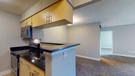 Located at 1450 Washington Blvd in Stamford, Connecticut, this single-floor residence offers a thoughtfully designed layout with a clean, modern aesthetic throughout. The galley-style kitchen is a standout feature, equipped with stainless steel appliances — including a full-size refrigerator, electric range, and microwave — complemented by dark granite countertops, light wood cabinetry with contemporary hardware, and durable tile flooring. A peninsula counter extends the kitchen into the adjoining living area, creating a natural transition between spaces. The living and sleeping areas are finished with plush wall-to-wall carpeting and neutral-toned walls, lending a warm and comfortable ambiance. Windows throughout the unit admit generous natural light and frame views of the surrounding Stamford cityscape and neighboring architecture. The bathroom is outfitted with a full tub-shower combination featuring white tile surround, matching vanity cabinetry, and tile flooring consistent with the kitchen. The overall layout is efficiently organized, with distinct zones for living, cooking, and bathing. The unit's neutral palette and consistent finishes create a cohesive and move-in-ready environment well-suited for urban living in downtown Stamford.