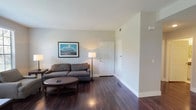 Located at 901 Westcreek Lane in Thousand Oaks, California, this single-floor residence offers a thoughtfully designed layout with a cohesive, neutral aesthetic throughout. Rich, dark hardwood flooring flows through the living, dining, and kitchen areas, creating a warm and polished foundation for the space.

The living room is generously proportioned, featuring multiple windows fitted with slatted blinds that allow natural light to filter in while maintaining privacy. The room provides ample space for comfortable seating arrangements and is accented by framed wall art that adds a touch of character.

The dining area connects seamlessly to the living space and is highlighted by a ceiling fan and a full glass sliding door that opens to a private outdoor patio, offering views of surrounding greenery. This indoor-outdoor connection enhances the overall sense of openness.

The kitchen is well-equipped with stainless steel appliances, including a gas range, microwave, and refrigerator, complemented by white shaker-style cabinetry and grey countertops. The bedroom features plush carpeting, mirrored sliding closet doors, windows with garden views, and a dresser with television. The bathroom includes a combination tub and shower with clean, white finishes and dark wood-toned vanity accents.