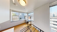 Located on the fourth floor at 1815 Bellevue Ave in Seattle's vibrant Capitol Hill neighborhood, Unit 401 is a thoughtfully designed studio that maximizes every inch of its single-floor layout. Large corner windows flood the main living area with abundant natural light while framing sweeping views of the surrounding Seattle skyline and neighboring greenery — a standout feature of this elevated unit.

The living and workspace area is anchored by the generous corner window configuration, offering an inspiring setting well-suited for a desk or reading nook. Warm hardwood-style flooring runs throughout the main space, adding a touch of warmth to the clean, white-walled interior.

The kitchenette is efficiently outfitted with crisp white cabinetry extending to the ceiling for ample storage, a smooth white countertop workspace, and built-in appliances including a microwave and compact refrigerator — all neatly integrated into the design.

The bathroom features a walk-in shower, a wall-mounted vanity with mirror, overhead cabinetry, and durable flooring in a warm golden tone, maintaining the unit's clean and functional aesthetic throughout.

Flush-mount lighting fixtures with a modern gold accent detail complete the polished look. This unit offers a bright, efficient urban living experience in one of Seattle's most walkable and dynamic neighborhoods.