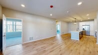 Located in Elgin, IL, this single-story, 3-bedroom, 2-bathroom home offers a thoughtfully designed floor plan with modern finishes throughout. The open-concept kitchen and living area serves as the heart of the home, featuring light hardwood flooring, recessed lighting, and a seamless flow between spaces. The kitchen is a standout, showcasing a large center island with a striking quartz waterfall countertop, undermount sink with a matte black faucet, crisp white upper cabinetry, gray lower cabinets with black hardware, stainless steel appliances, and a stylish pendant light fixture above the island. The spacious living room connects to the rest of the home via wide doorways, and a secondary room provides outdoor access through a paneled door with transom windows, filling the space with natural light. The primary bedroom offers generous proportions, plush carpeting, multiple windows with neighborhood views, and direct access to a closet. Additional bedrooms are also carpeted and well-lit with large windows. The primary bathroom features gray cabinetry, a glass-enclosed walk-in shower with black-framed doors, and wood-look flooring. The secondary bathroom includes a gray vanity, a full tub-shower combo with white tile surround, and black accent hardware throughout.