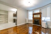 Located at 36 Maitland St in Toronto's vibrant Church-Wellesley neighbourhood, this 2-bedroom, 1-bathroom unit showcases a thoughtful blend of historic character and contemporary finishes across a well-planned single floor layout.

The living room is an immediate standout, featuring rich hardwood floors, a decorative cast-iron fireplace framed by a handsome wood mantel, and a generous bay window that floods the space with natural light. Cast-iron radiators throughout speak to the building's heritage roots.

The galley-style kitchen is well-appointed with dark espresso cabinetry, white quartz countertops, stainless steel appliances including a fridge and range, and a classic black-and-white octagonal tile floor — a timeless detail that adds charm and character. A window above the sink brings in additional natural light.

Both bedrooms are finished with the same warm hardwood flooring and neutral grey walls, offering a calm and versatile backdrop. The primary bedroom provides a comfortable footprint, while the second bedroom features its own window with a radiator beneath it. A dedicated closet adds practical storage.

The bathroom continues the black-and-white tile motif, with clean white wall tiles and a crisp, minimal aesthetic. Built-in shelving in the hallway area provides additional storage within the unit's efficient and functional layout.