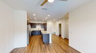 Located at 201 Wildwood Blvd in Forney, TX, this well-appointed one-bedroom, one-bathroom unit offers a thoughtfully designed open-concept layout. The kitchen is a standout feature, showcasing rich dark espresso cabinetry reaching to the ceiling, light granite countertops, a large center island ideal for dining or prep work, and a full suite of stainless steel appliances including a refrigerator, electric range, and dishwasher. The kitchen flows seamlessly into the living area, which is finished with warm hardwood-style flooring, recessed lighting, and a ceiling fan. A set of glass doors opens to a private balcony, allowing natural light to fill the space and providing outdoor views. The bedroom is carpeted for comfort, features a ceiling fan, and receives natural light through a large window. It connects to a generously sized walk-in closet with built-in shelving and dual hanging rods, offering excellent storage. The bathroom is finished with hardwood-style flooring, a dark-framed vanity mirror, a single-sink vanity, a soaking tub, and a tiled walk-in shower. A hallway connects the bedroom wing to the main living area, completing this clean and modern single-floor layout.
