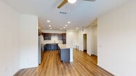 Located at 201 Wildwood Blvd in Forney, TX, this well-appointed one-bedroom, one-bathroom unit offers a thoughtfully designed open-concept layout. The kitchen is a standout feature, showcasing rich dark espresso cabinetry reaching to the ceiling, light granite countertops, a large center island ideal for dining or prep work, and a full suite of stainless steel appliances including a refrigerator, electric range, and dishwasher. The kitchen flows seamlessly into the living area, which is finished with warm hardwood-style flooring, recessed lighting, and a ceiling fan. A set of glass doors opens to a private balcony, allowing natural light to fill the space and providing outdoor views. The bedroom is carpeted for comfort, features a ceiling fan, and receives natural light through a large window. It connects to a generously sized walk-in closet with built-in shelving and dual hanging rods, offering excellent storage. The bathroom is finished with hardwood-style flooring, a dark-framed vanity mirror, a single-sink vanity, a soaking tub, and a tiled walk-in shower. A hallway connects the bedroom wing to the main living area, completing this clean and modern single-floor layout.