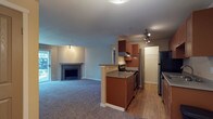 This single-floor residence offers a thoughtfully designed layout that balances comfort and functionality. The open-concept living area is spacious and carpeted, anchored by a fireplace and sliding glass doors that allow natural light to pour in while providing direct outdoor access. Track lighting adds a modern touch to the space.

The galley-style kitchen is efficiently arranged with warm medium-toned wood cabinetry lining both sides, stainless steel appliances including a refrigerator, electric range with vent hood, and dishwasher, along with a double stainless steel sink and ample counter space. A peninsula separates the kitchen from the living area, creating a natural transition between the two spaces. Light hardwood-style flooring runs throughout the kitchen, providing a clean contrast to the carpeted living areas.

The bedrooms are generously sized, carpeted, and include baseboard heating and closet storage. One bedroom features a sliding-door closet with built-in rods, while another offers a bifold-door closet.

The two bathrooms are finished with wood-toned cabinetry and light countertops. One bathroom includes a wide vanity with dual mirrors and bright vanity lighting, while the other features a glass-door shower enclosure and a single vanity with a large mirror. Both bathrooms have hardwood-style flooring for easy maintenance.
