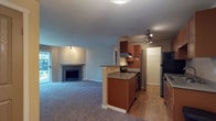 This single-floor residence offers a thoughtfully designed layout that balances comfort and functionality. The open-concept living area is spacious and carpeted, anchored by a fireplace and sliding glass doors that allow natural light to pour in while providing direct outdoor access. Track lighting adds a modern touch to the space.

The galley-style kitchen is efficiently arranged with warm medium-toned wood cabinetry lining both sides, stainless steel appliances including a refrigerator, electric range with vent hood, and dishwasher, along with a double stainless steel sink and ample counter space. A peninsula separates the kitchen from the living area, creating a natural transition between the two spaces. Light hardwood-style flooring runs throughout the kitchen, providing a clean contrast to the carpeted living areas.

The bedrooms are generously sized, carpeted, and include baseboard heating and closet storage. One bedroom features a sliding-door closet with built-in rods, while another offers a bifold-door closet.

The two bathrooms are finished with wood-toned cabinetry and light countertops. One bathroom includes a wide vanity with dual mirrors and bright vanity lighting, while the other features a glass-door shower enclosure and a single vanity with a large mirror. Both bathrooms have hardwood-style flooring for easy maintenance.