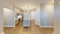 Located at 2815 Capital Blvd in Raleigh, NC, this single-floor unit offers a thoughtfully designed layout with contemporary finishes throughout. The open-concept kitchen serves as a central hub, featuring light wood cabinetry, granite countertops, a subway tile backsplash in a soft seafoam hue, stainless steel appliances including a side-by-side refrigerator, electric range, and built-in microwave, and a central island with an integrated sink and pendant lighting above. Hardwood-style flooring runs throughout the main living areas, lending warmth and cohesion to the space.

The living area is bright and welcoming, benefiting from natural light through large windows with a transom detail above the exterior door. Neutral-toned walls and clean white baseboards give the space a fresh, move-in-ready aesthetic.

The bedrooms feature plush carpeting and multiple electrical outlets for convenience. Each bathroom is well-appointed — one includes a walk-in glass-enclosed shower with tile surround, while another offers a tiled soaking tub and shower combination. Both bathrooms provide direct access to walk-in closets outfitted with wire shelving systems, maximizing storage efficiency throughout the unit.