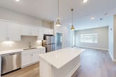 Located at 6276 Newton Rd in Haslett, Michigan, this well-designed single-floor residence offers 2 bedrooms and 4 bathrooms within a thoughtfully laid-out floor plan. The open-concept kitchen is a standout feature, showcasing white shaker cabinetry, a large quartz-topped island, stainless steel appliances including a refrigerator, range, microwave, and dishwasher, and stylish pendant lighting. The kitchen flows seamlessly into the living room, which is bathed in natural light from large windows and features light hardwood-style flooring. A glass door in the living area provides direct access to a private balcony. The bedrooms are carpeted for comfort, with the primary bedroom offering a generous footprint, walk-in closets with wire shelving systems, and good natural light. Additional walk-in closet space is found throughout the unit, providing practical storage solutions. The hallway connects the living spaces efficiently, and the four bathrooms ensure convenience for residents and guests. Neutral, warm-toned walls and clean white trim maintain a cohesive, contemporary aesthetic throughout the entire residence.