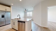 This well-appointed one-bedroom, one-bathroom residence offers a thoughtfully designed layout with modern finishes throughout. Light wood-style flooring flows seamlessly across the entire space, creating a cohesive and contemporary aesthetic.

The open-concept kitchen serves as a central hub, anchored by a peninsula island topped with granite countertops and a dual-basin undermount sink with a matte black faucet. Stainless steel appliances — including a French door refrigerator, electric range with microwave, and dishwasher — complement the two-toned cabinetry featuring light gray-beige uppers and lowers accented by sleek black hardware. A classic white subway tile backsplash adds a clean, timeless touch. Recessed lighting illuminates the kitchen, while a ceiling fan overhead serves the adjacent living area, which also benefits from natural light streaming through a window with blinds.

The bedroom is a calm, neutral retreat with a window for natural light and direct access to a dedicated closet. The full bathroom is well-equipped with a granite-topped vanity, gray cabinetry with matching black hardware, a large mirror with overhead lighting, and a full tub-shower combination featuring floor-to-ceiling marble-style tile surround with matte black fixtures.