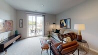 This single-floor residence offers a thoughtfully designed layout that balances comfort and functionality across its key living spaces. The open-concept kitchen is a standout feature, outfitted with dark espresso cabinetry, granite countertops, stainless steel appliances including a refrigerator, microwave, and range, and a central island with bar seating — ideal for both cooking and casual dining. Hardwood-style flooring adds warmth and continuity throughout the kitchen area.

The living room is carpeted and generously proportioned, bathed in natural light from large sliding glass doors that open onto a private balcony. The balcony offers views of the surrounding landscape, including distant mountain scenery. The living space accommodates a comfortable seating arrangement and provides a relaxed, inviting atmosphere.

The bedroom is a serene retreat, featuring plush carpeting, ample natural light from a large window with sheer drapery, and sufficient space for a full bedroom suite. The neutral gray palette throughout the room creates a calm and restful environment.

The bathroom is finished with tile flooring, a granite-topped vanity with dark cabinetry, and a large mirror with overhead lighting, lending a clean and polished look. Overall, the residence presents a cohesive, modern aesthetic with neutral tones and quality finishes throughout.