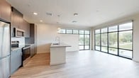 Located at 7501 Jefferson St in Albuquerque, NM, this thoughtfully designed 2-bedroom, 2-bathroom unit offers a modern aesthetic complemented by clean lines and quality finishes throughout. The open-concept living, dining, and kitchen area serves as the heart of the home, anchored by a sleek kitchen island with an integrated sink and pendant lighting overhead. The kitchen is equipped with stainless steel appliances, dark taupe cabinetry, a white tile backsplash, and light wood-style flooring that flows seamlessly throughout the entire unit. Expansive floor-to-ceiling windows and a large glass-panel wall in the living area flood the space with natural light and offer pleasant outdoor views. A central hallway connects the private quarters, where two well-proportioned bedrooms feature neutral walls, natural light from well-placed windows, and ample closet space — including a walk-in closet outfitted with wire shelving. The two bathrooms are finished with contemporary gray vanities, quartz-style countertops, and tiled tub-shower combinations. The overall ambiance is bright, clean, and modern, making this a highly functional and stylish living space.