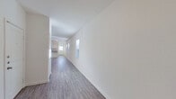 This single-floor home offers a clean, modern aesthetic throughout, characterized by crisp white walls, durable hardwood-style flooring, and an abundance of natural light streaming through multiple windows. The open-concept layout connects the living area to the kitchen seamlessly, creating an expansive, airy feel ideal for both everyday living and entertaining. The kitchen is thoughtfully designed with white shaker-style cabinetry, granite countertops, stainless steel appliances including a range, microwave, and refrigerator, and a peninsula with a double-basin sink — a functional and stylish centerpiece of the home. The living area is generously proportioned with recessed lighting and smooth, neutral-toned walls that complement any décor style. Bedrooms are carpeted for comfort, offering a quiet retreat, and benefit from natural light through blinds-fitted windows. The primary bedroom includes a spacious walk-in closet outfitted with wire shelving and hanging rods. Two bathrooms serve the home: one featuring a tub-shower combination and the other a stand-alone shower with sliding glass doors and built-in shelving — both finished with hardwood-style flooring and clean white fixtures. The overall ambiance is fresh, neutral, and move-in ready.