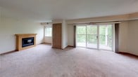 This single-floor residence offers a thoughtfully designed layout with a variety of functional spaces throughout. The expansive living room serves as the heart of the home, featuring a gas fireplace, large sliding glass doors that open to a private balcony with outdoor views of lush greenery, and an additional window that fills the room with natural light. The kitchen is well-equipped with warm oak cabinetry, a full suite of white appliances including a refrigerator, electric range, built-in microwave, and dishwasher, along with light-toned countertops and easy-care tile flooring. The bedrooms are carpeted and generously sized, each with wide windows that frame views of surrounding trees. The primary suite includes a spacious walk-in closet outfitted with built-in shelving, hanging rods, and a dresser unit for ample storage. Two full bathrooms serve the residence — one featuring a tub/shower combination and the other a standalone shower — both with tile flooring and wood-toned vanity cabinetry. A dedicated laundry room houses a full-size washer and dryer with overhead shelving. Textured ceilings and neutral tones throughout lend a clean, consistent aesthetic to the entire space.