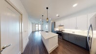 Located at 208 E Broadway Ave in Fort Worth, Texas, this single-floor residence offers a well-designed open-concept layout with modern finishes throughout. The kitchen serves as a central focal point, featuring a large island with a white quartz countertop and an integrated stainless steel sink with a commercial-style faucet. Two-tone cabinetry — pairing slate-gray lower cabinets with white uppers — is complemented by a white subway tile backsplash and stainless steel appliances, including a range and refrigerator. Industrial-style pendant lighting adds a distinctive design touch above the island.

The living area extends naturally from the kitchen, showcasing dark hardwood flooring and a ceiling fan, with French doors providing natural light and outdoor views. Bedrooms feature plush carpeting, ceiling fans, and large windows that bring in natural light.

The bathrooms are finished with large-format tile flooring, white quartz vanity countertops, slate-gray cabinetry, framed mirrors, and subway-tiled tub-shower combinations. At least one bathroom includes accessible grab bars. Walk-in closets with built-in shelving provide ample storage. The overall aesthetic is clean, contemporary, and cohesive throughout the space.