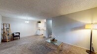 Located at 15301 NE 20th Street in Bellevue, Washington, this single-floor residence offers a well-organized layout designed for comfortable everyday living. The living room is finished with plush carpeting, a textured ceiling, and a large window that invites natural light and views of surrounding greenery, complemented by baseboard heating along the exterior wall. Adjacent to the living area, a dedicated dining space features wood-style plank flooring and a pendant light fixture overhead, creating a distinct and functional zone for meals and gatherings. The kitchen is equipped with white cabinetry, a coil-top electric range, a dishwasher, and laminate countertops, all finished with a clean, practical aesthetic. The bedroom is generously proportioned with soft carpeting, a sliding-door closet with built-in rod and shelving, a window with outdoor views, and baseboard heating. The full bathroom includes a soaking tub with a shower and curtain rod, finished in neutral tones. A dedicated laundry closet houses a stacked washer and dryer unit, adding everyday convenience. Throughout the unit, neutral gray walls and textured ceilings provide a cohesive, understated backdrop.