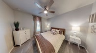 This single-story home in San Antonio, Texas offers a thoughtfully designed layout with a neutral color palette and modern finishes throughout. The living room is bright and welcoming, featuring light wood-style flooring, large windows with floor-to-ceiling drapes that allow generous natural light, and direct access to the outdoors through a glass-paneled door. A dining area adjacent to the kitchen is highlighted by a stylish pendant light fixture and warm wood tones. The kitchen is well-equipped with white shaker cabinetry, light quartz countertops, a subway tile backsplash, and stainless steel appliances, including a range and over-the-range microwave. The bedrooms are carpeted and comfortably sized, each featuring windows with blinds and drapes. One bedroom includes a ceiling fan with light, while another offers a walk-in closet and an ensuite bathroom. The bathrooms are finished with white vanity cabinetry, quartz countertops, large mirrors, and light tile flooring. The primary bathroom includes a full tub-shower combination. Overall, the home presents a clean, contemporary aesthetic suited for comfortable everyday living in a well-connected San Antonio neighborhood.