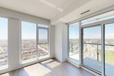 Located at 40 Lagerfeld Dr in Brampton, Ontario, this modern 2-bedroom, 1-bathroom unit offers a well-designed layout with contemporary finishes throughout. Light wood-tone flooring flows consistently across all rooms, complementing the clean white walls and creating a bright, cohesive aesthetic.

The kitchen is a standout feature, equipped with stainless steel appliances including a built-in microwave, electric range, and dishwasher. Light wood cabinetry pairs with a sleek quartz-topped island and a grey glass backsplash, while large windows frame sweeping views of the surrounding landscape.

Both bedrooms are bright and well-proportioned, featuring floor-to-ceiling windows that flood the rooms with natural light and offer impressive elevated views over Brampton's residential neighbourhoods and roadways. Mirrored sliding closet doors add a functional and space-enhancing touch to the bedrooms.

The bathroom is finished in a clean, minimalist style with white subway tile, a glass-enclosed walk-in shower, and modern chrome fixtures.

The hallway connects the rooms efficiently and includes a mirrored closet, enhancing the sense of space. Throughout the unit, the elevated position of the building ensures abundant natural light and panoramic sightlines, making this a bright and functional urban living space.