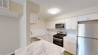 Located at 72 Rossway Ave in Rossford, Ohio, this single-floor, two-bedroom, one-bathroom home offers a thoughtfully designed layout with modern finishes throughout. The combined kitchen and living area forms the heart of the home, where the kitchen stands out with crisp white shaker cabinetry, subway tile backsplash, marble-look quartz countertops, and a full suite of stainless steel appliances including a gas range, over-the-range microwave, and refrigerator. Light wood-tone luxury vinyl plank flooring extends through the living area, which is brightened by a sliding glass door that opens to a private balcony with outdoor views of surrounding greenery. Both bedrooms are finished with neutral carpet and offer a comfortable, restful atmosphere. The primary bedroom provides a generous footprint with a dedicated closet space. The full bathroom features wood-look LVP flooring, a white vanity with a clean countertop, and a tub-shower combination with brushed nickel fixtures. A hallway connects the bedrooms and bathroom, with two closets providing ample storage. Neutral warm-beige walls and consistent, updated finishes give the entire home a clean, move-in-ready feel.
