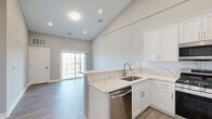 Located at 2421 Bristol Road in Warrington, PA, this thoughtfully designed one-bedroom, one-bathroom residence offers a bright and modern living experience across a well-utilized single floor. The open-concept layout is anchored by a striking kitchen featuring white shaker cabinetry, marble-look quartz countertops, a tile backsplash, stainless steel appliances including a gas range, built-in microwave, dishwasher, and refrigerator, and a peninsula that separates the kitchen from the living area. Soaring vaulted ceilings in the main living space create an impressive sense of openness, while recessed lighting and wood-look plank flooring throughout lend a clean, contemporary aesthetic. Sliding glass doors in the living area allow for natural light and outdoor access. The spacious primary bedroom is fitted with large multi-pane windows that frame pleasant outdoor views of the surrounding neighborhood, and benefits from direct access to a dedicated closet. The full bathroom is elegantly appointed with marble-look tile on the floors and tub surround, a white vanity with quartz countertop, and a tub-shower combination. A hallway and additional closet provide practical storage solutions, completing this well-appointed and move-in-ready residence.