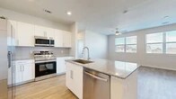 This well-appointed 1-bedroom, 1-bathroom unit is designed with a clean, modern aesthetic and thoughtful use of space across a single floor. The open-concept kitchen and living area serves as the heart of the home, featuring light-toned hardwood-style flooring, neutral walls, and ample natural light streaming through large windows fitted with blinds. The kitchen is outfitted with crisp white shaker cabinetry, granite countertops, a tile backsplash, and a full suite of stainless steel appliances including a side-by-side refrigerator with ice maker, range, built-in microwave, and dishwasher. A central kitchen island with an undermount sink adds both prep space and a casual dining option. The living area is bright and open, with a ceiling fan and dual windows offering views of the surrounding neighborhood. The bedroom is a comfortable, well-lit retreat with its own ceiling fan, a large window, and access to a spacious walk-in closet equipped with wire shelving for organized storage. The bathroom features wood-style flooring, a granite-topped vanity, and a full tub-shower combination with elegant marble-style tile surround.
