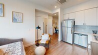 Unit 404 at 410 5th Ave is a thoughtfully designed studio on the fourth floor in downtown Olympia, Washington. The open-concept layout maximizes every inch of the space, seamlessly integrating the kitchen, living, and sleeping areas under recessed lighting and light-toned ceilings. Light wood-style flooring runs throughout, lending warmth and visual continuity.

The kitchen is outfitted with stainless steel appliances — including a full-size refrigerator, electric range with over-the-range microwave, and dishwasher — paired with crisp white cabinetry that extends to the ceiling for ample storage. A floor-to-ceiling window wall anchors the living and sleeping area, flooding the space with natural light and offering sweeping views of the Olympia skyline and beyond.

A dedicated hallway connects the main living area to a compact dining nook and the full bathroom. The bathroom features a wide vanity with white cabinetry, generous counter space, a large mirror, and a stacked washer and dryer unit — a rare and practical convenience. The hallway itself provides additional visual separation between living and utility zones.

This studio offers a clean, modern aesthetic with efficient use of space, making it a well-appointed urban retreat in the heart of Olympia.