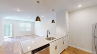 Located at 270 Main St in Sayreville, NJ, this well-appointed one-bedroom, one-bathroom unit offers a thoughtfully designed single-floor layout with a bright, contemporary aesthetic throughout. The open-concept kitchen serves as a central highlight, featuring crisp white shaker cabinetry, quartz countertops, a classic tile backsplash, and a full suite of stainless steel appliances including a gas range, microwave, refrigerator, and dishwasher. A peninsula with a matte black faucet and undermount sink is illuminated by sleek pendant lights, seamlessly connecting to the living area. The living space is finished with warm hardwood-style flooring and recessed lighting, with a window allowing natural light to fill the room. The bedroom offers a comfortable, carpeted retreat with a natural light source and direct access to a dedicated walk-in closet outfitted with wire shelving and hanging rods for ample storage. The bathroom is finished with large-format tile flooring, a gray vanity with a framed mirror and modern black fixtures, and a tiled shower, creating a clean and polished look. A hallway connects all areas with ease, completing this efficiently designed and move-in-ready home.