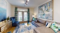 Located at 159 W Kinderton Way in Bermuda Run, NC, this single-floor residence offers a thoughtfully designed layout that blends functionality with contemporary style. The kitchen is equipped with gray shaker-style cabinetry, granite countertops, a classic white subway tile backsplash, and a full suite of stainless steel appliances including a range, built-in microwave, dishwasher, and refrigerator. A built-in wine rack adds a distinctive touch to the kitchen's character.

The living area is bright and welcoming, featuring track lighting, warm hardwood-style flooring, and French doors that open directly to an outdoor patio, allowing natural light to flow throughout. The space is accented by bold, colorful artwork and a coordinated blue-toned décor palette that carries through the entire unit.

The bedroom is a serene retreat, complete with a ceiling fan, generous windows dressed with patterned curtains that invite ample natural light, and hardwood-style flooring. The bathroom is finished with gray cabinetry, granite countertops, a dual vanity, and a tiled walk-in shower, complemented by direct access to a well-organized walk-in closet with built-in shelving. The cohesive coastal-inspired design makes this space both practical and visually inviting.